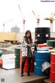 A woman standing in front of a pile of colorful barrels.