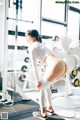 A woman in a white shirt and leggings standing in a gym.