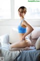 A woman in a blue bra and panties sitting on a bed.