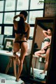 A woman in a black bikini standing in front of a mirror.