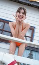 A woman in an orange bikini posing on a boat.