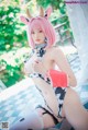 A woman with pink hair wearing a cow costume.