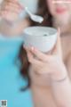 A woman holding a bowl of soup with a spoon in it.