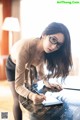 A woman sitting at a table writing on a piece of paper.