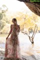 A woman in a long dress standing in front of a river.