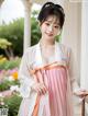 A woman in a pink and white hanbok posing for a picture.