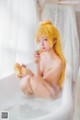 A naked woman sitting in a bathtub eating a donut.