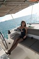 A woman in a black dress sitting on a boat.