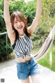 A woman in a striped top and denim shorts posing for a picture.