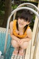 A woman in a yellow bathing suit sitting on the edge of a pool.