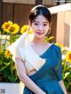 A woman in a blue dress standing in front of sunflowers.