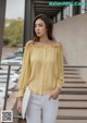 a woman wearing a yellow blouse and white pants