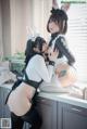 A couple of women in bunny costumes sitting on top of a kitchen counter.