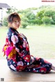 A woman in a kimono sitting on a wooden floor.