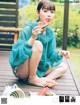 A woman sitting on a wooden deck eating a slice of watermelon.