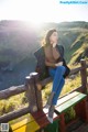 A woman sitting on a wooden bench in a field.