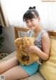 A woman sitting on a bed holding two teddy bears.