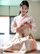 A woman in a pink and white hanbok sitting on the floor.