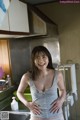 A woman standing in a kitchen next to a sink.